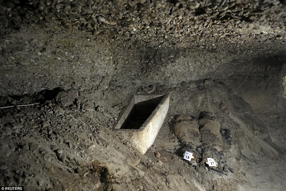 Two of the mummies are pictured next to a tomb inside the burial site.