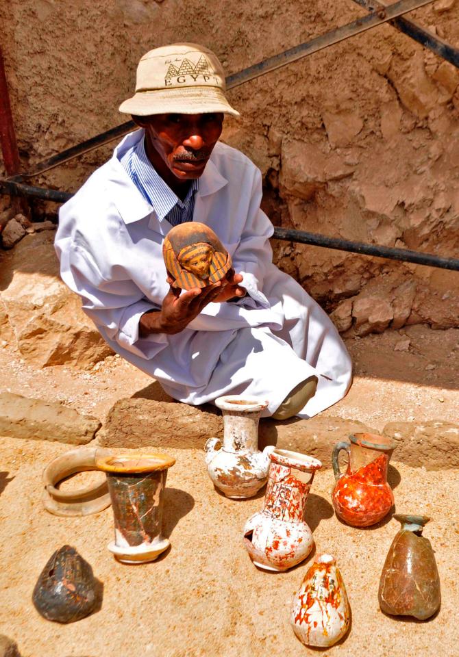 A member of an Egyptian archaeological team holds up one of the artefacts 