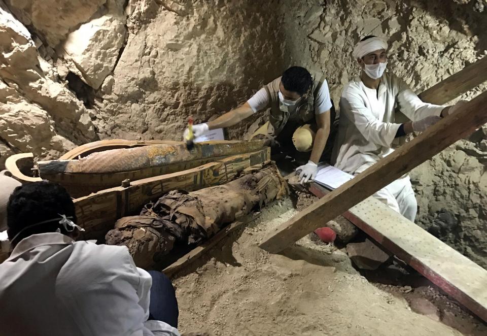 archaeologists wearing white masks and latex gloves inspected the coffins 