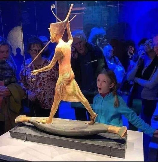 Une statuette en bois doree du roi toutankhamon se dresse sur un bateau en bois peint pour representer un bateau en papyrus